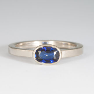 Ring, 2mm flat comfort fit w/ bezel set Blue Sapphire (supplied and recut) oval 7x5mm .95ct., 14KW, size 5.5