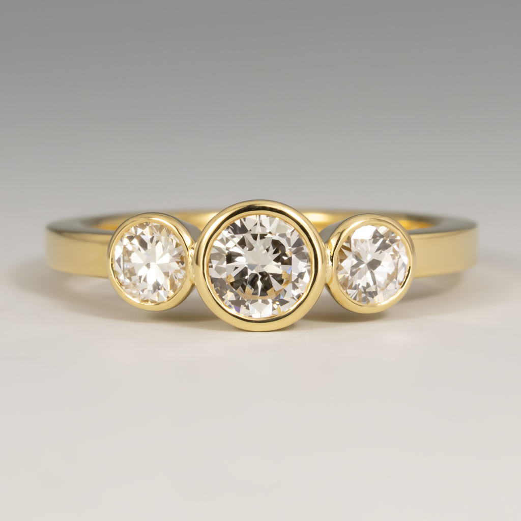 Ring, 3 in line, Diamonds supplied: Center 4.38mm .25ct. 2 flanking stones:3.43mm .15ct, 3.39mm .15ct. bezel set, 2mm comfort fit flat band, 18KY, size 4.5